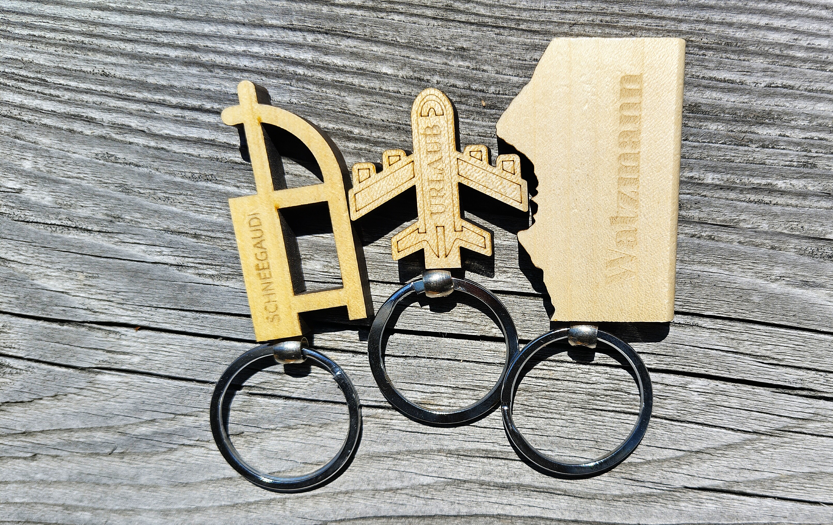 Drei gravierte Holzanhänger mit regionalen Motiven auf Holzhintergrund